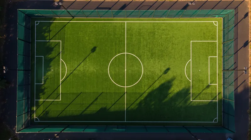 Illustration: aerial view of a football pitch at sunset